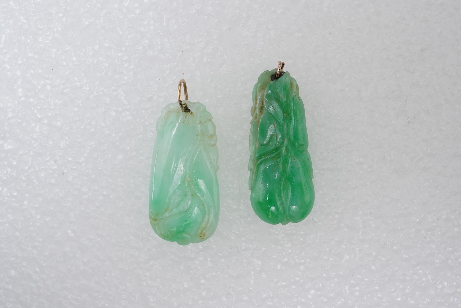 Two carved jadeite pendants, China, early 20th century, each carved to depict a fruiting vine of bitter gourd, longest 3.5cm excluding bail, combined gross weight approximately 10 grams